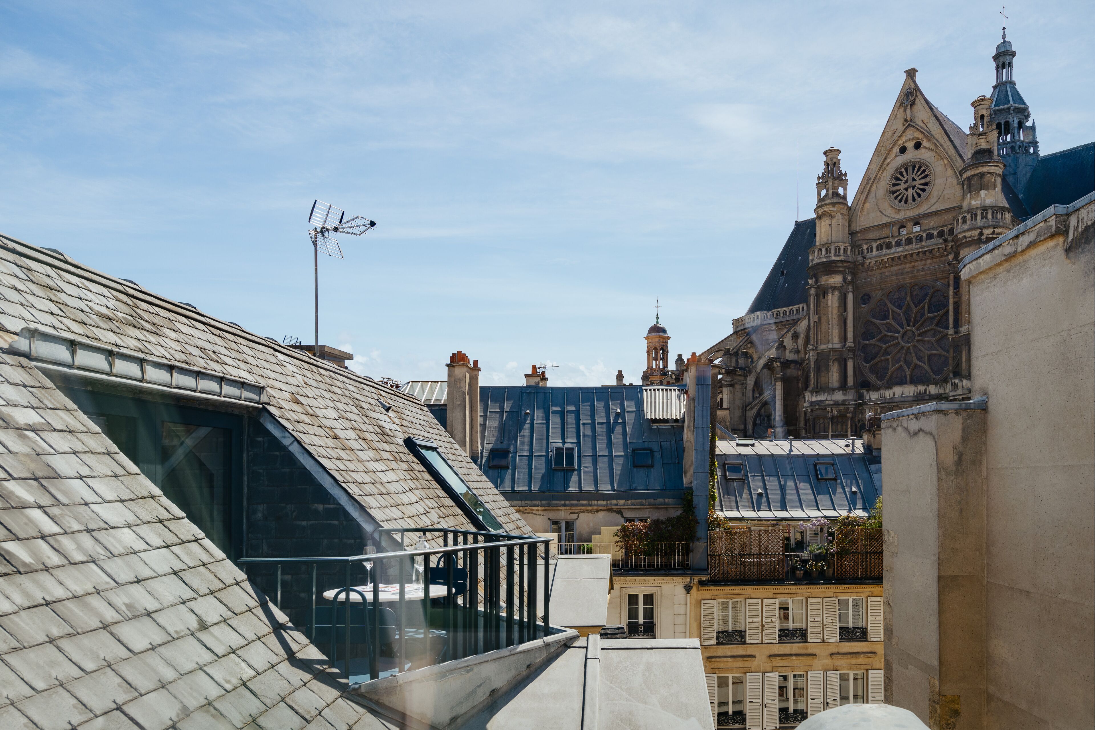 A building with a sloped roof, a balcony with a railing, and a large window.