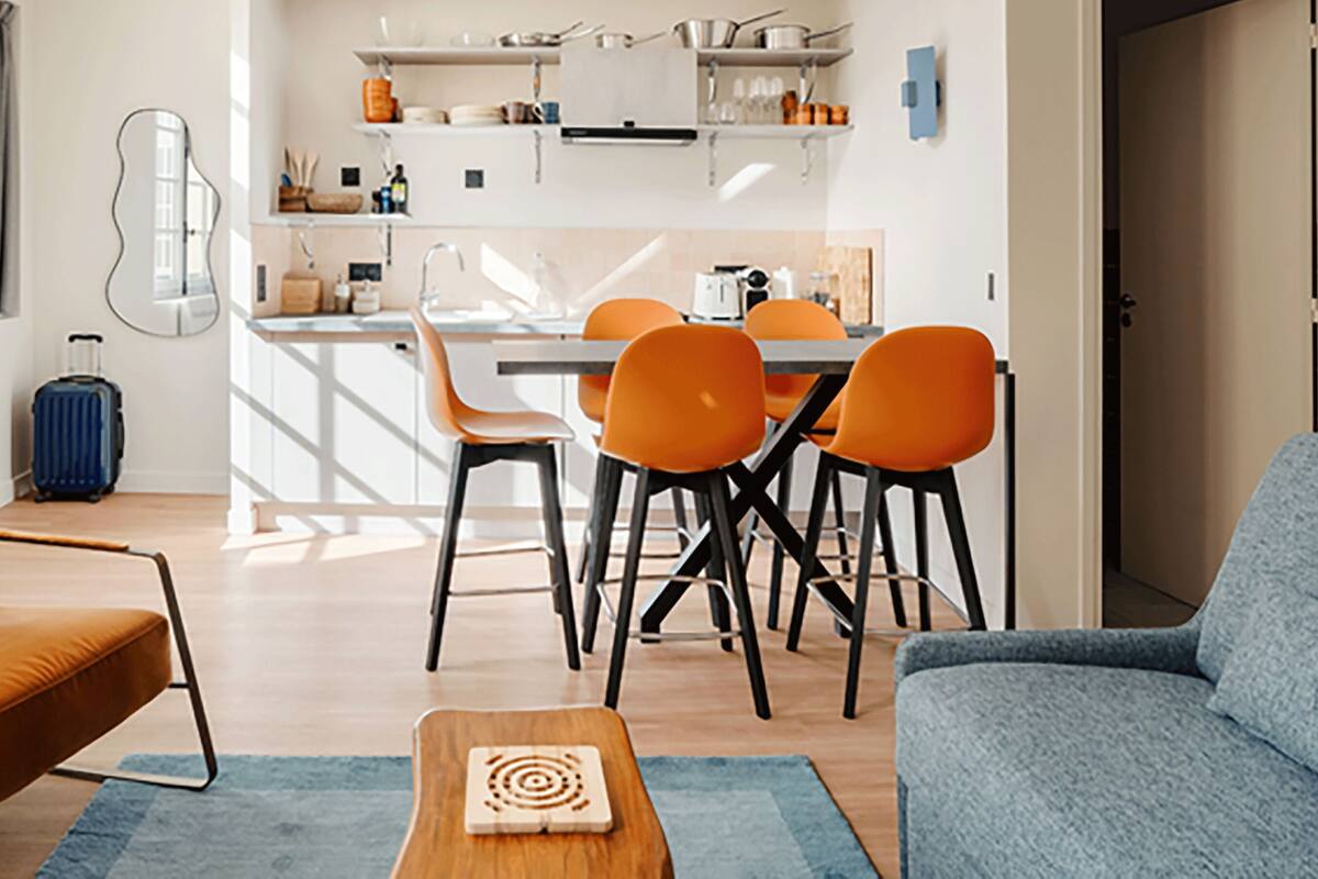 A modern living room with a sofa, a coffee table, and a dining area with chairs and a table.