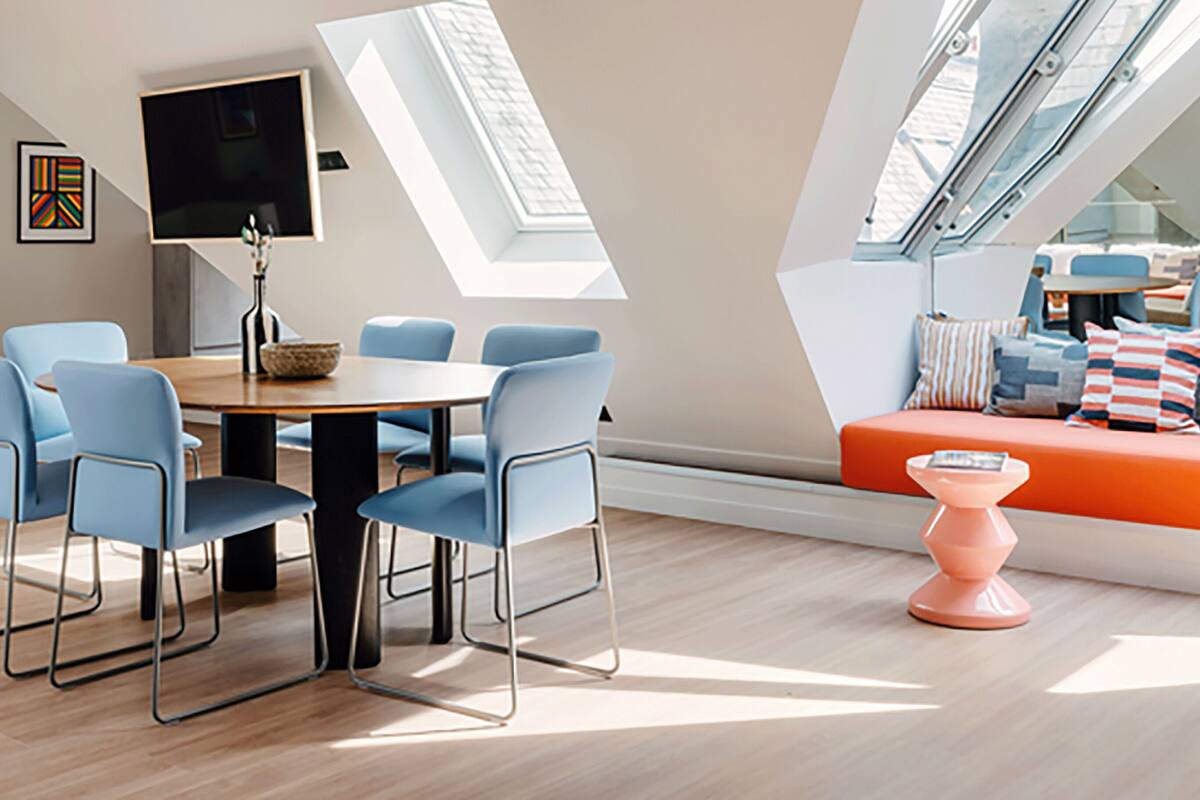 A modern loft apartment with a dining area, a sofa, and a staircase.