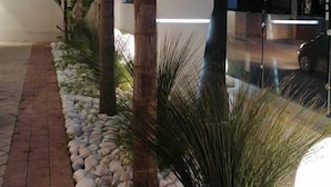 A sign for the Hotel President with a modern design, surrounded by palm trees and a paved walkway. - Hotel Presidente (Porto Cesareo)