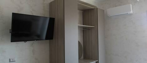 Una camera da letto moderna con televisione integrata, armadio e un piccolo angolo salotto.
