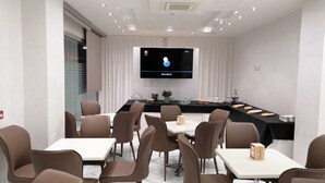 A conference room with a long table, multiple chairs, a television screen, and a whiteboard. - Hotel Presidente (Porto Cesareo)