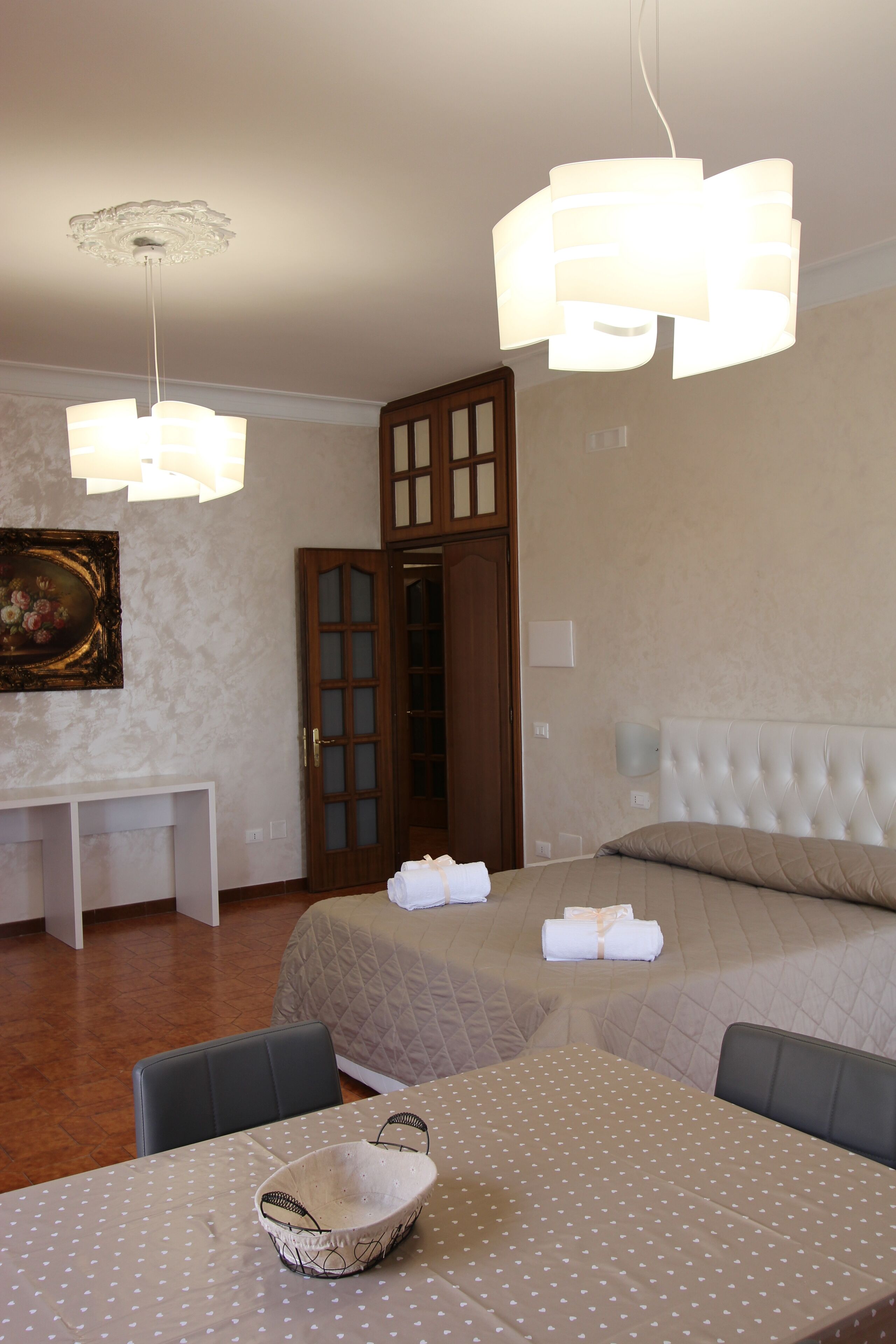 Ein Hotelzimmer mit zwei Betten, einem Esstisch mit punktiertem Tischläufer, einem weißen Korb und einem Bild an der Wand.