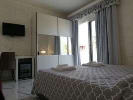 Una habitación de hotel con cama, escritorio, televisión y minibar.