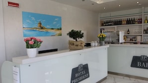 A hotel reception desk with a painting of a lighthouse, a plant, and a sign reading "HOTEL PRESIDENT". - Hotel Presidente (Porto Cesareo)
