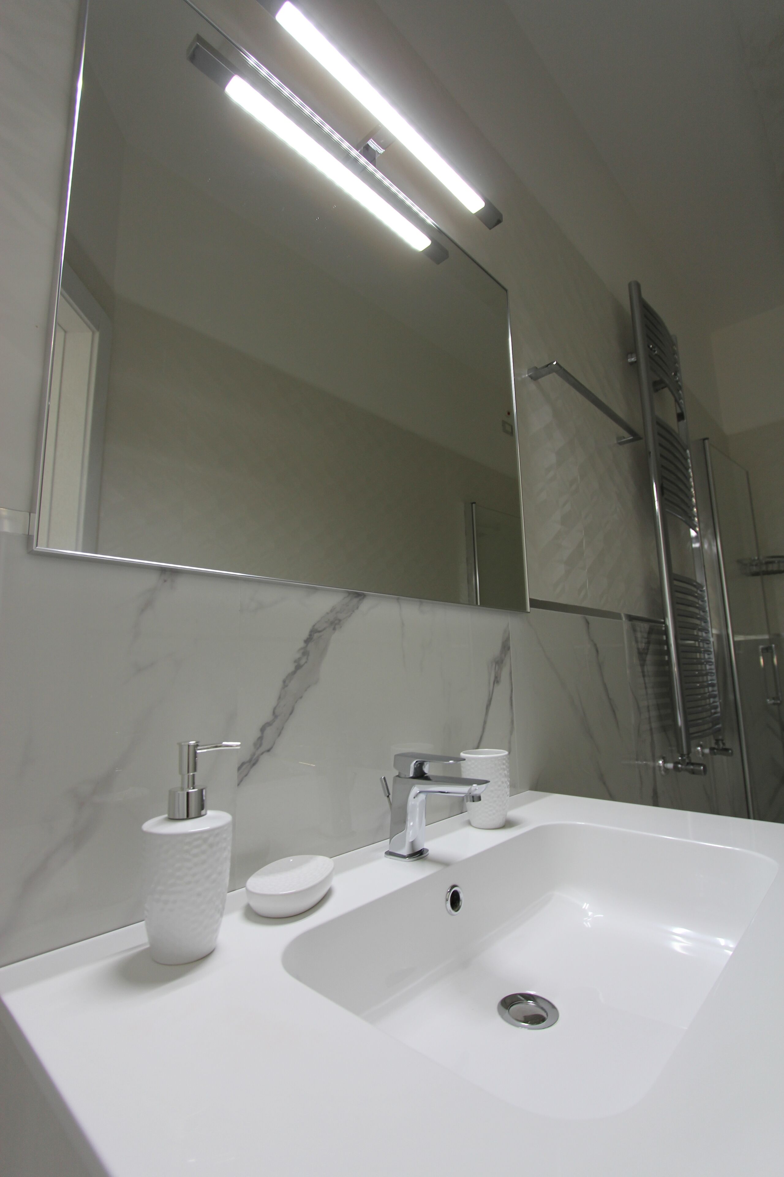 A bathroom with a white sink, a mirror, a towel rack, and a shower area.
