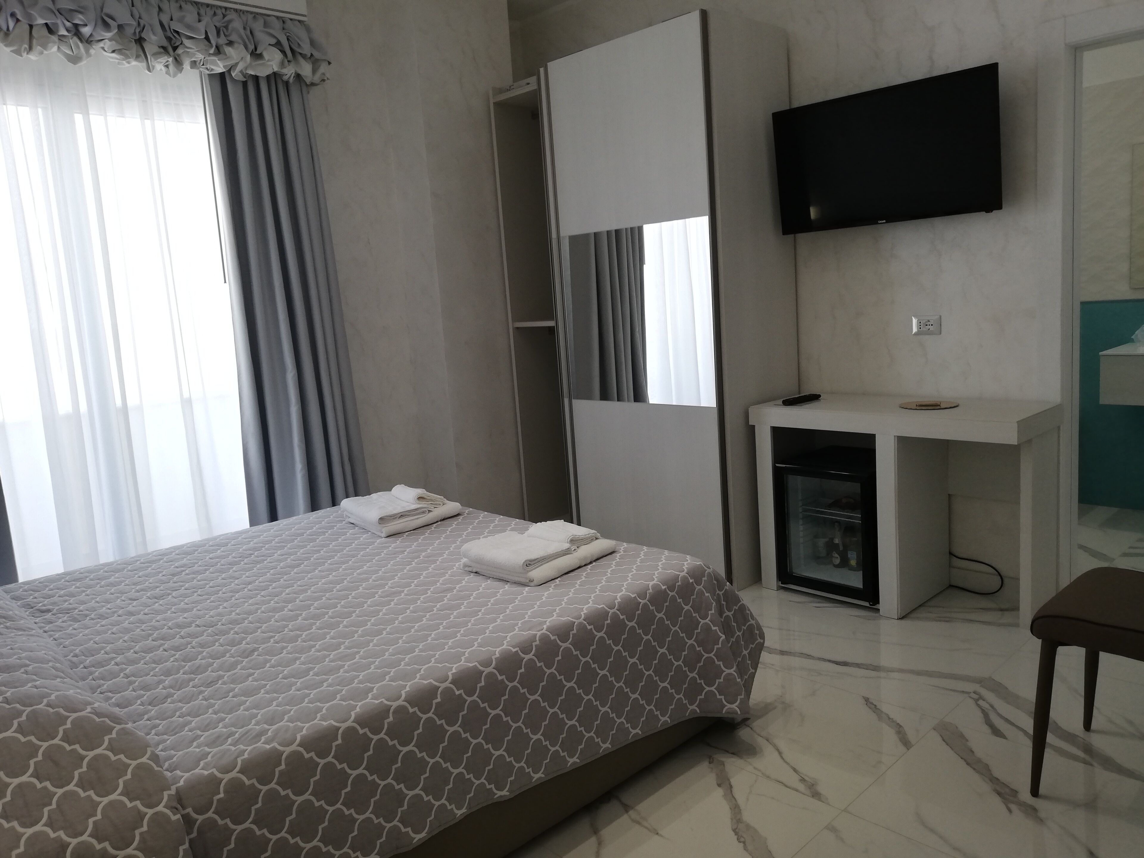 A hotel room with a bed, a desk, a television, and a wardrobe.