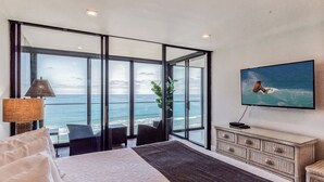 Ein Schlafzimmer mit großem Fenster und Meerblick, einem Bett, einem Fernseher und einer Pflanze.