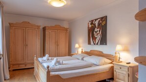 A bedroom with a wooden bed, two nightstands with lamps, a wardrobe, and a painting on the wall. - Apartment Kitz Thirty Nine - near AreitXpress (Zell am See)