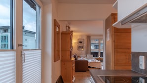 A narrow hallway leading to a bedroom with a bed, a wooden wardrobe, and a window with blinds. - Apartment Kitz Thirty Nine - near AreitXpress (Zell am See)