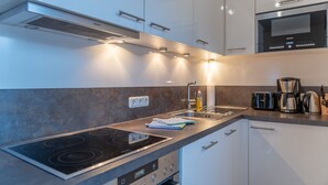 A modern kitchen with white cabinets, a black stove, and stainless steel appliances. - Apartment Kitz Thirty Nine - near AreitXpress (Zell am See)