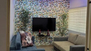Ein Wohnzimmer mit Wandmuster, einem Flachbildfernseher, zwei Sofas und einem Couchtisch.