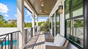 A covered outdoor deck with a pool, wicker furniture, and large windows. - Casa al Mare|Easy Beach Access|Private Pool|Golf Cart (Seagrove)