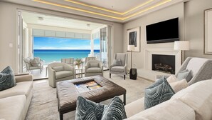 Un salon spacieux avec vue sur l’océan, une cheminée et un téléviseur à écran plat.