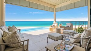 Un espace extérieur abrité, aménagé avec des sièges, et offrant une vue sur la plage et l’océan.