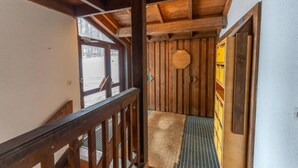 Un interior de madera con una escalera de metal, una puerta de madera y un armario amarillo.