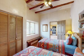 Traditional bedroom with a wardrobe, bench, and two beds, featuring a rustic design with exposed beams.