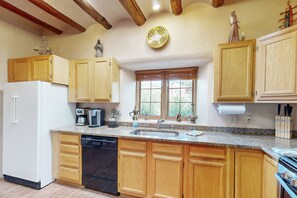 Enjoy cooking in this well-equipped kitchen with a dishwasher, stove, and oven, and take in the view of the surrounding greenery.
