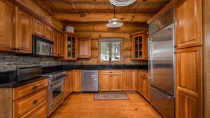 A wooden kitchen with a stainless steel refrigerator, oven, and microwave. - Luxury Log Cabin-Windham Mountain.  Amazing sunsets, large lawn, deck, fireplace (Windham)