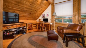 A cozy log cabin interior with a wooden ceiling, a television, a desk, a computer, a leather sofa, and storage trunks. - Luxury Log Cabin-Windham Mountain.  Amazing sunsets, large lawn, deck, fireplace (Windham)