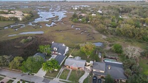An aerial view of a residential area with houses, a large water body, and surrounding vegetation. - Huge Yard with Marsh Views! | Minutes to Beach/DT! (St. Augustine)