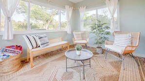 A cozy room with a wooden bench, two wicker chairs, a round table, and a ceiling fan. - Huge Yard with Marsh Views! | Minutes to Beach/DT! (St. Augustine)