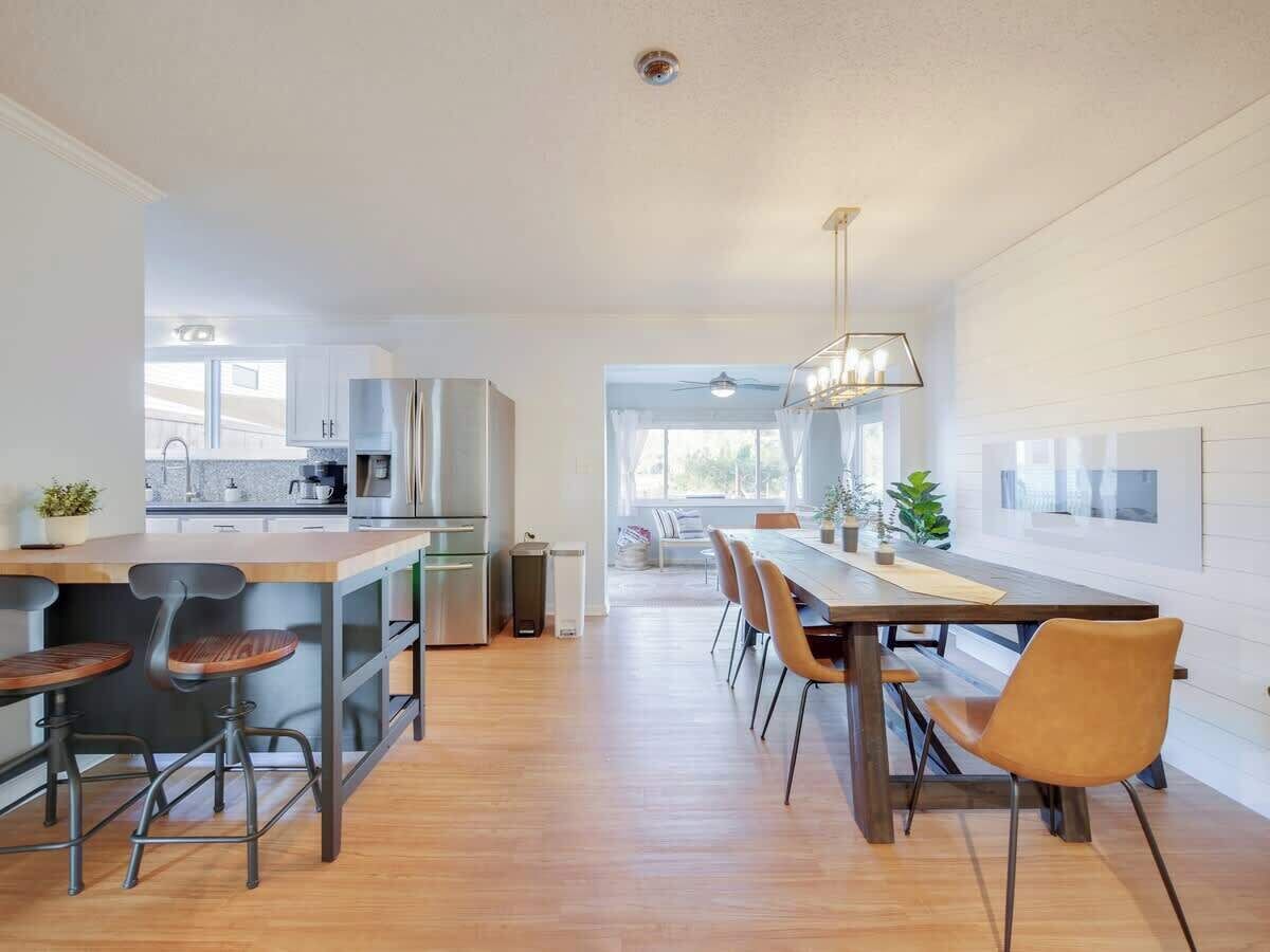 A modern kitchen with a central island, bar stools, and a dining area with chairs.