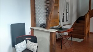 A room with a wooden ceiling, a dining area with a table and chairs, a sofa with patterned cushions, and a staircase leading to another level. - Country house between loire and sologne (Mézières-lez-Cléry)