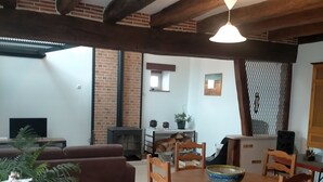 A dining area with a wooden table and chairs, a brick wall, and a hanging light fixture. - Country house between loire and sologne (Mézières-lez-Cléry)