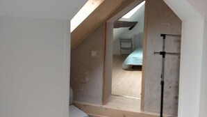 A narrow attic bedroom with a sloped ceiling and skylight, a bed, and a small seating area. - Country house between loire and sologne (Mézières-lez-Cléry)