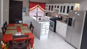 A kitchen with a central island, white cabinets, a refrigerator, and a dining table with chairs.