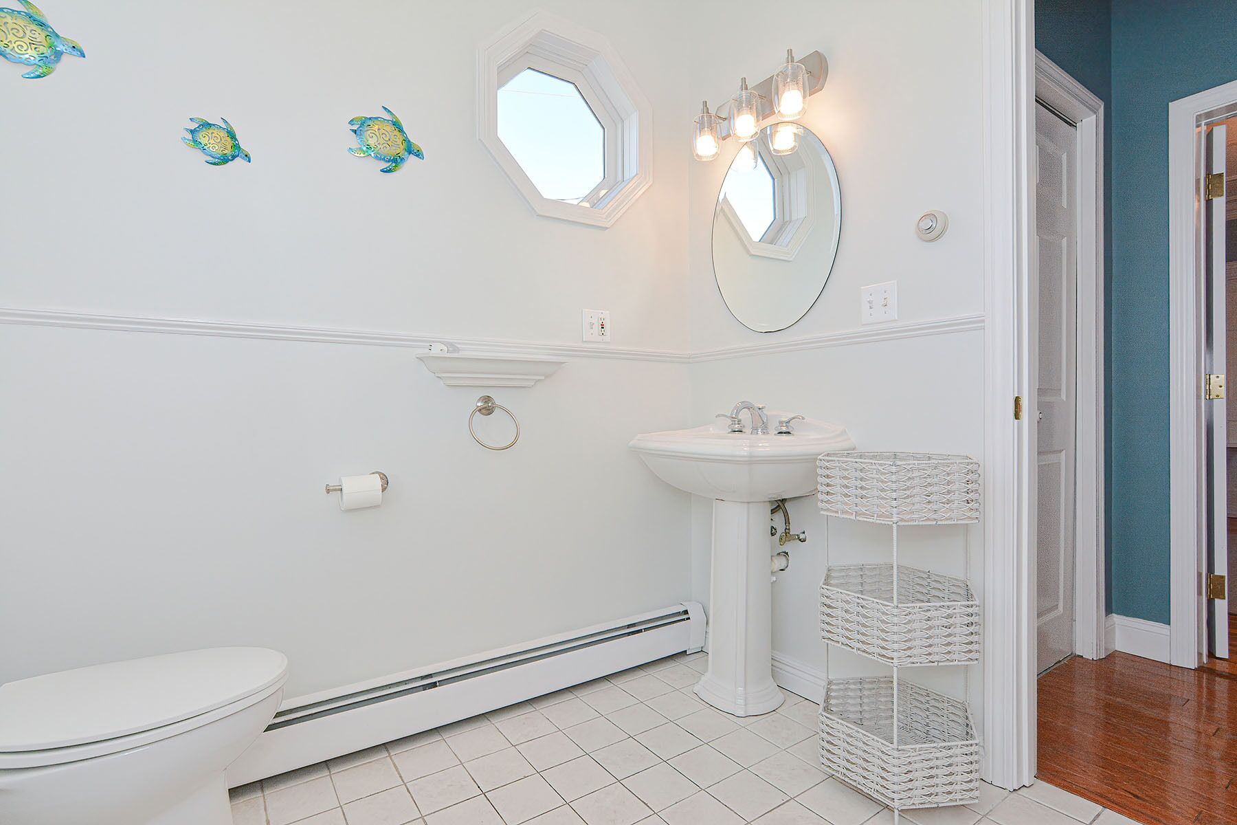 Ein Badezimmer mit Toilette, Waschtisch, einem Spiegel mit Beleuchtung und Wanddekoration.