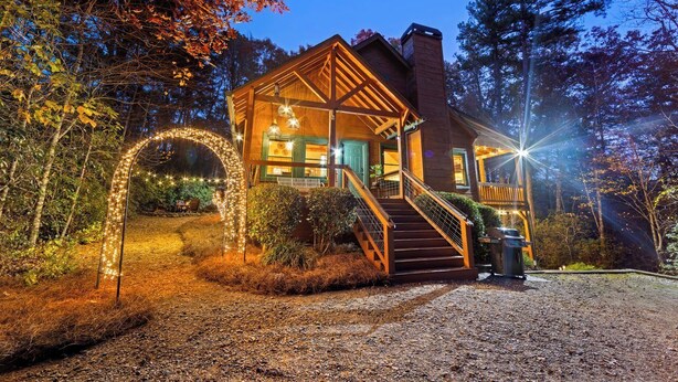 Une cabane rustique avec une façade en bois, une véranda et un escalier menant à l’entrée.