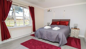 Una camera da letto con un letto, tende rosse, un termosifone, un comodino e una finestra con vista sull'esterno.