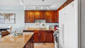 Eine Küche mit Holzausstattung, einer Granitabdeckung, einem Kühlschrank und einem Spülbecken.