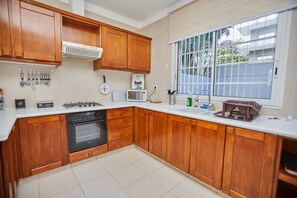 Une cuisine avec des meubles de rangement en bois, une cuisinière à gaz, un four à micro-ondes et un évier.