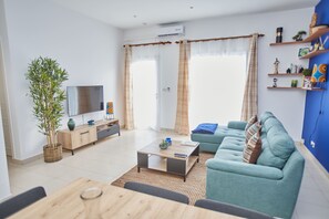Un salon moderne avec un canapé, un téléviseur et un coin repas.