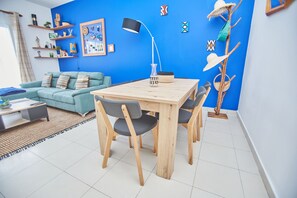 Un salon moderne avec un mur d’accent bleu, une table à manger en bois et un canapé.