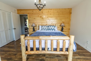 Un lit à cadre en bois, recouvert d’une couvre-lit bleue et blanche, avec deux lampes de chevet et une tête de lit en bois.