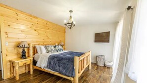 Una stanza con rivestimenti in legno, un letto, comodini, una lampada e un lampadario.