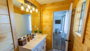 Un bagno in legno con lavandino, specchio e portasciugamani.