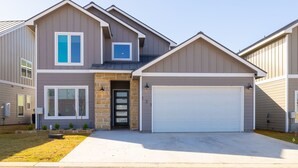 A modern two-story house with a garage, large windows, and a stone foundation.