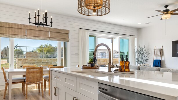 A modern kitchen with a large island, white cabinetry, and a stainless steel dishwasher.