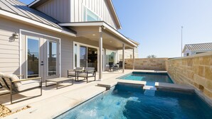 A house with a swimming pool, outdoor seating, and a covered patio area.