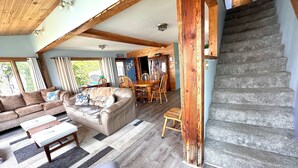 Un vaste espace de vie comprenant un canapé en cuir, une table à manger et un escalier.