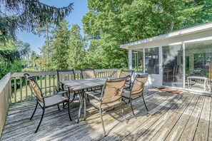 Enjoy outdoor dining or relaxation on the deck with a table and chairs, surrounded by lush greenery.