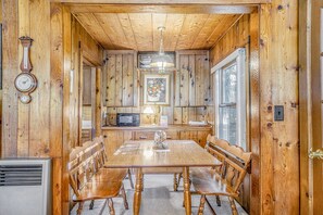 Cozy room with a wooden dining table, bench, and kitchenette area.