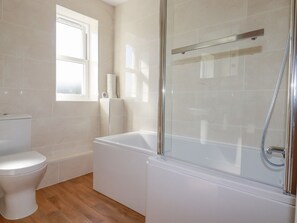 Un baño con inodoro, bañera y cabina de ducha con mampara de vidrio.