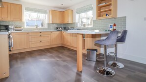 Una cucina moderna con mobili in legno, un frigorifero in acciaio inox e un'area bar con sgabelli.