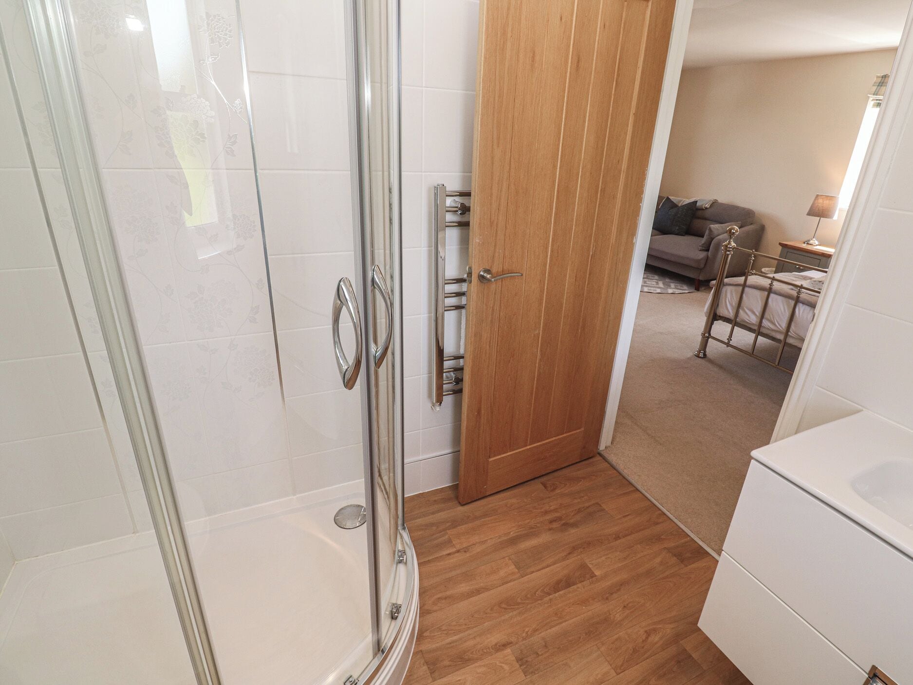 A bathroom with a glass shower enclosure, a wooden door, and a white toilet.